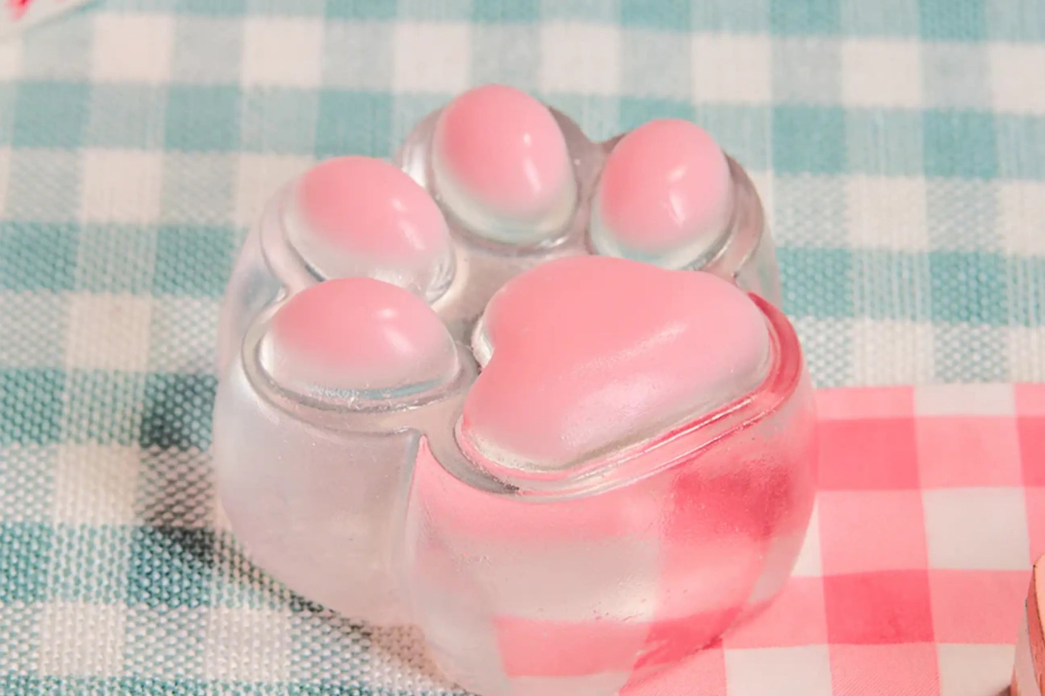 Pink Transparent Cat Paw Squishy placed on desk, clear silicone paw toy with pink jelly beans, cute kawaii desk accessory.