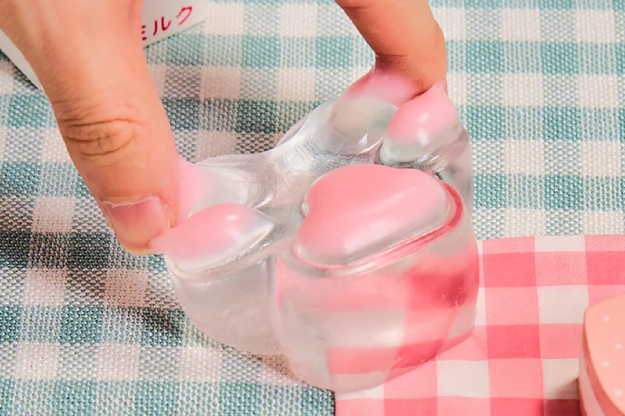 Hand squeezing Pink Transparent Cat Paw Squishy, soft silicone paw with pink jelly beans, stress relief fidget toy.
