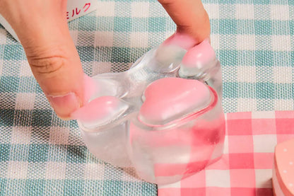 Hand squeezing Pink Transparent Cat Paw Squishy, soft silicone paw with pink jelly beans, stress relief fidget toy.